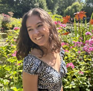 Margaux, standing in a garden, smiling